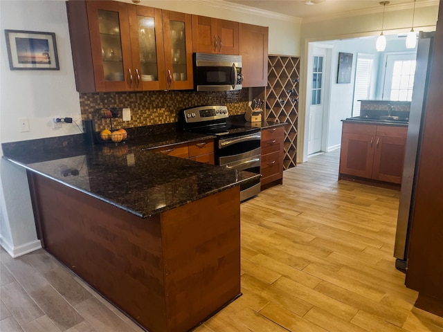 kitchen with pendant lighting, dark stone counters, light hardwood / wood-style floors, kitchen peninsula, and stainless steel appliances