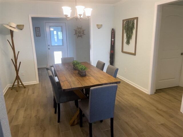 dining space featuring hardwood / wood-style flooring, ornamental molding, and an inviting chandelier