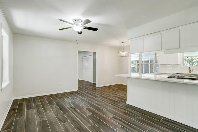 interior space with ceiling fan with notable chandelier and dark wood-type flooring