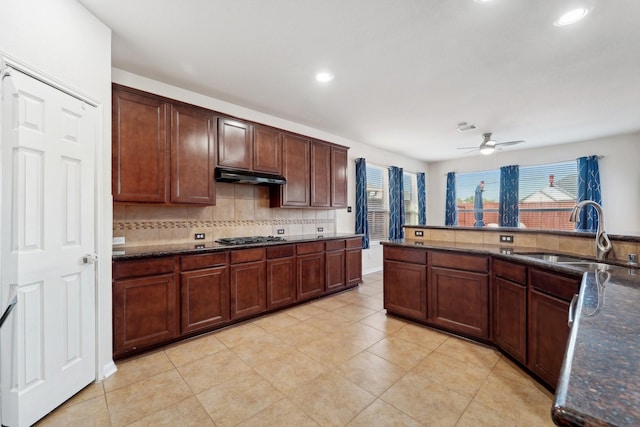 kitchen featuring dark stone countertops, ceiling fan, and sink