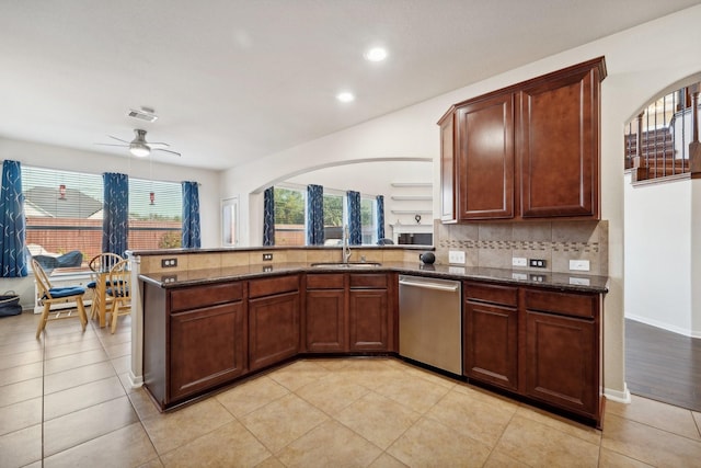 kitchen with dishwasher, dark stone counters, sink, ceiling fan, and kitchen peninsula