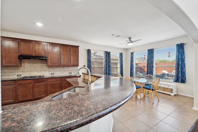 kitchen featuring ceiling fan, sink, tasteful backsplash, dark stone countertops, and light tile patterned flooring