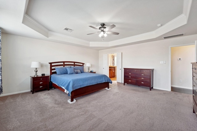 carpeted bedroom featuring a tray ceiling, ceiling fan, crown molding, and ensuite bathroom