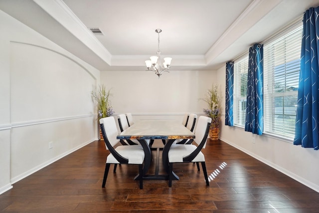 dining area featuring ornamental molding, dark hardwood / wood-style flooring, a tray ceiling, and a notable chandelier