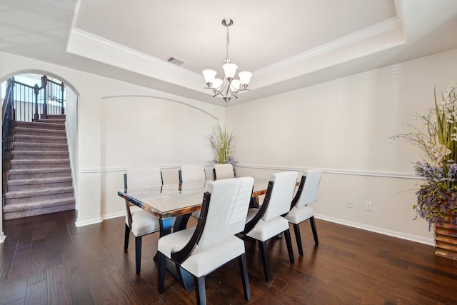 dining space featuring a chandelier, dark hardwood / wood-style flooring, a raised ceiling, and ornamental molding