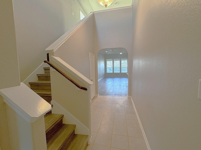 stairway with a high ceiling and tile patterned floors