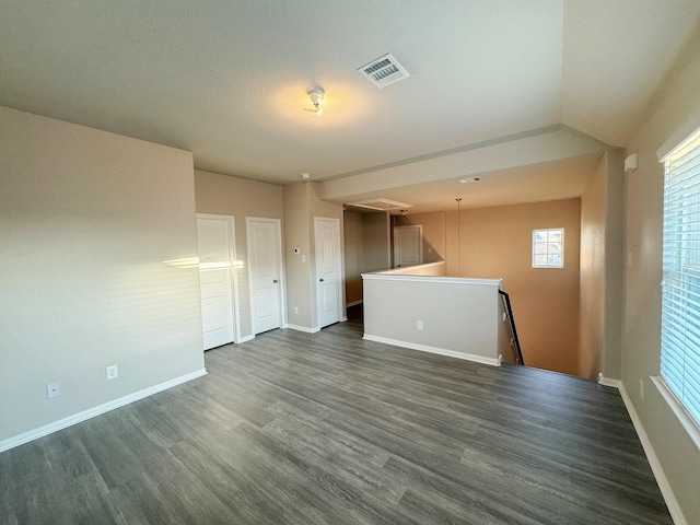 spare room with dark hardwood / wood-style flooring and vaulted ceiling