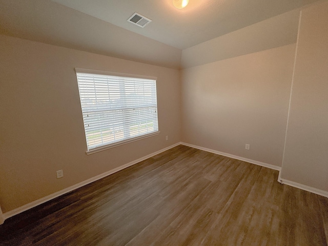 spare room with dark hardwood / wood-style flooring and vaulted ceiling