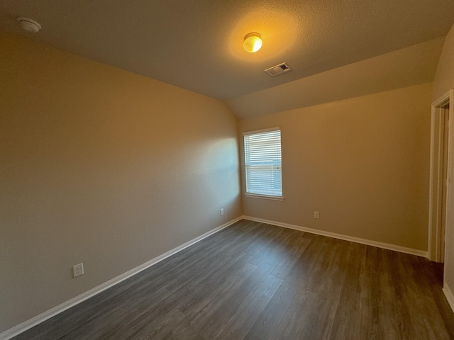 unfurnished room featuring dark hardwood / wood-style flooring, lofted ceiling, and a textured ceiling