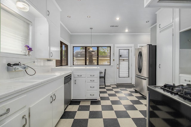 kitchen with stainless steel appliances, white cabinetry, hanging light fixtures, and crown molding