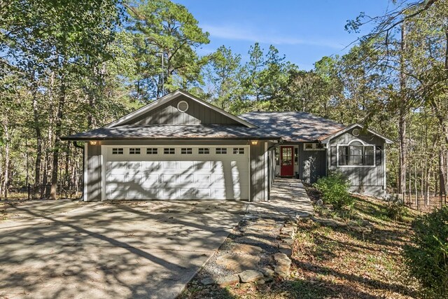 ranch-style house featuring driveway, roof with shingles, and an attached garage
