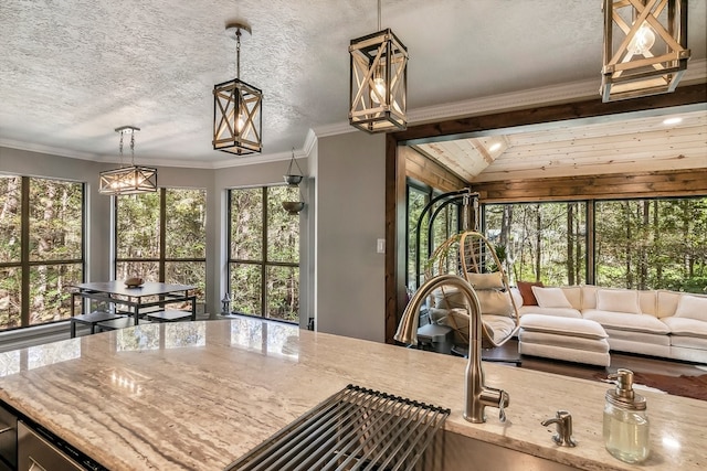 kitchen with crown molding, open floor plan, light stone counters, and a textured ceiling