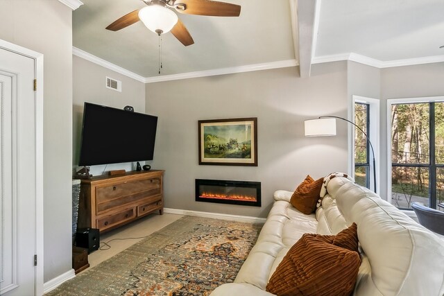 living area with crown molding, a glass covered fireplace, baseboards, visible vents, and ceiling fan