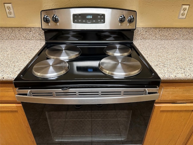 details featuring light stone counters and electric stove