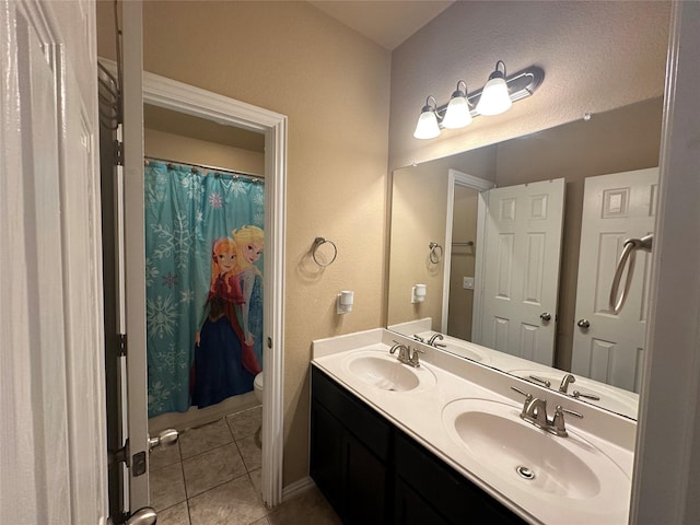 full bath with toilet, tile patterned floors, a sink, and double vanity