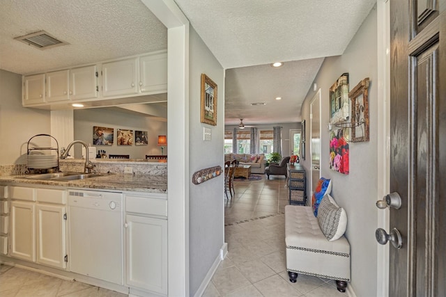 kitchen featuring white dishwasher, light stone countertops, a textured ceiling, light tile patterned floors, and sink