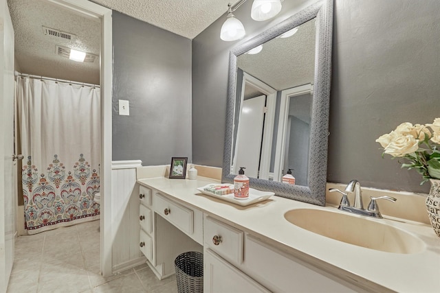 bathroom featuring vanity, walk in shower, a textured ceiling, toilet, and tile patterned floors