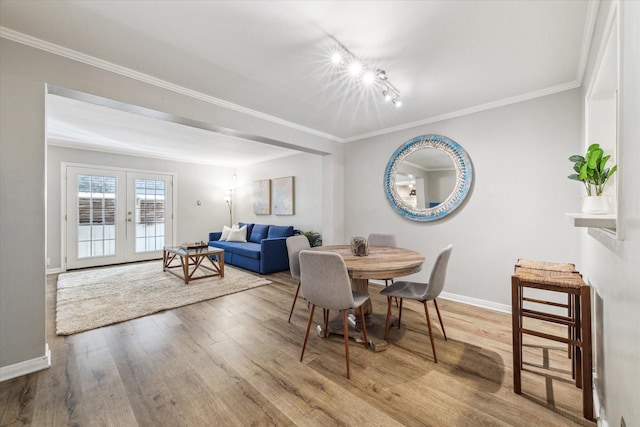 dining space featuring crown molding, french doors, track lighting, and hardwood / wood-style flooring