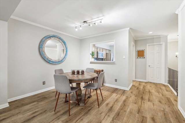 dining room featuring track lighting, light hardwood / wood-style flooring, and crown molding