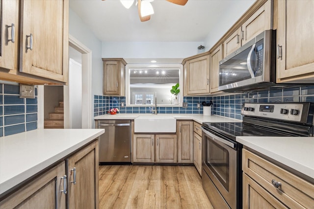 kitchen with ceiling fan, sink, stainless steel appliances, light hardwood / wood-style floors, and decorative backsplash