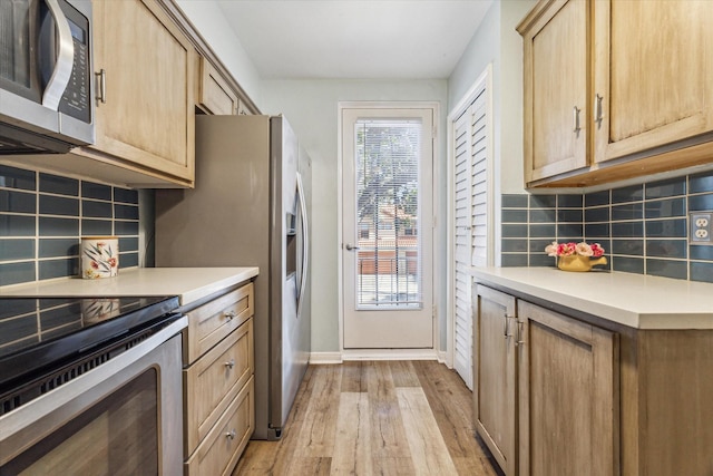 kitchen featuring light wood-type flooring, appliances with stainless steel finishes, backsplash, and light brown cabinetry