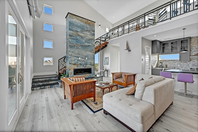 living room featuring a fireplace, high vaulted ceiling, and light hardwood / wood-style flooring