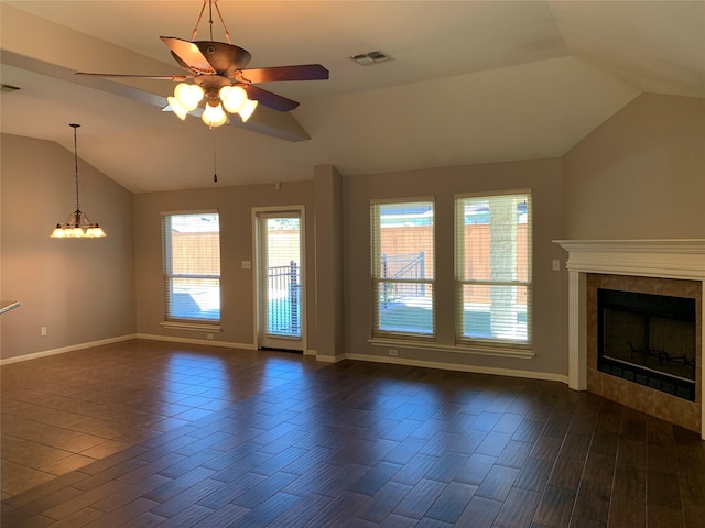 unfurnished living room with vaulted ceiling, a tiled fireplace, and ceiling fan with notable chandelier