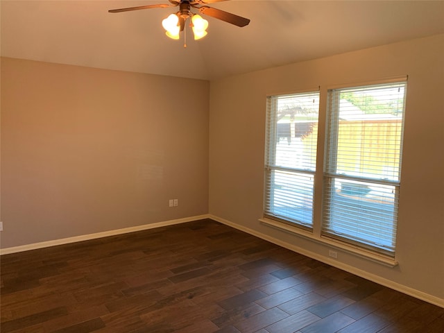 empty room with dark hardwood / wood-style flooring, vaulted ceiling, and ceiling fan