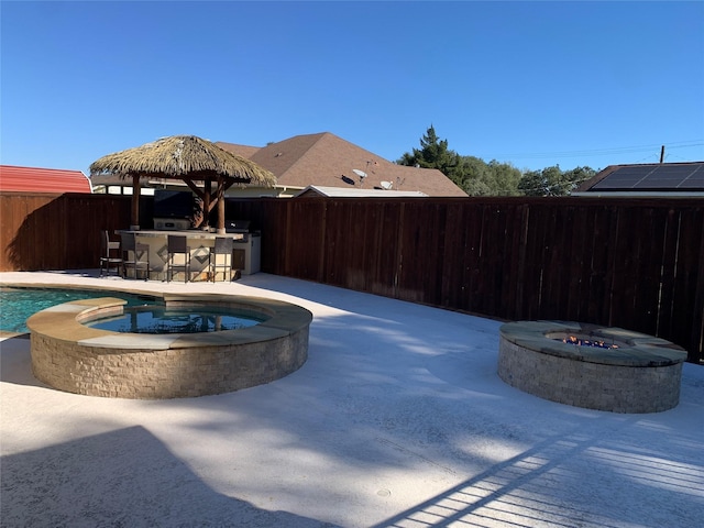 view of pool with a patio area, a bar, an in ground hot tub, and an outdoor fire pit