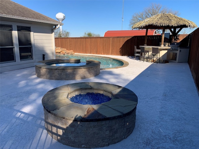 view of pool featuring an in ground hot tub, a bar, an outdoor kitchen, and a patio area