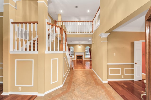 foyer with a towering ceiling, decorative columns, and ornamental molding