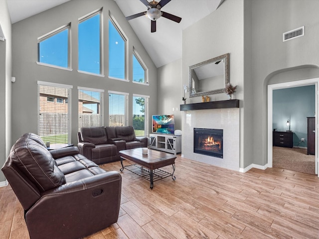 living room featuring a towering ceiling, plenty of natural light, and ceiling fan