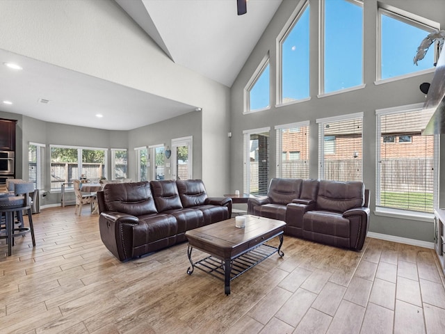 living room featuring ceiling fan, a towering ceiling, and a healthy amount of sunlight