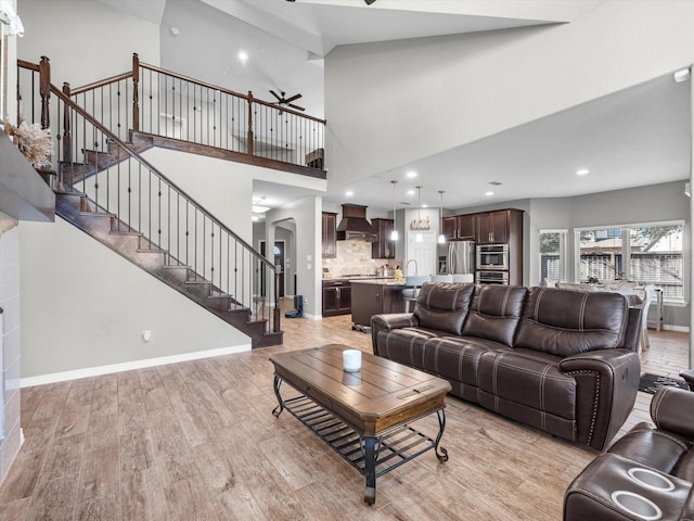 living room with sink, a towering ceiling, and light hardwood / wood-style floors