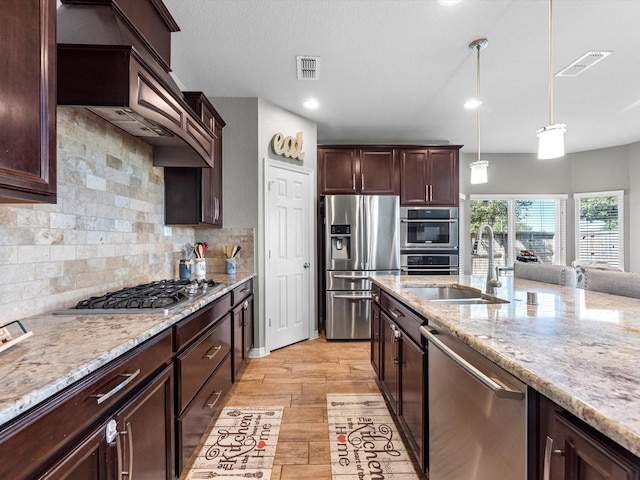 kitchen with pendant lighting, sink, light stone countertops, appliances with stainless steel finishes, and tasteful backsplash