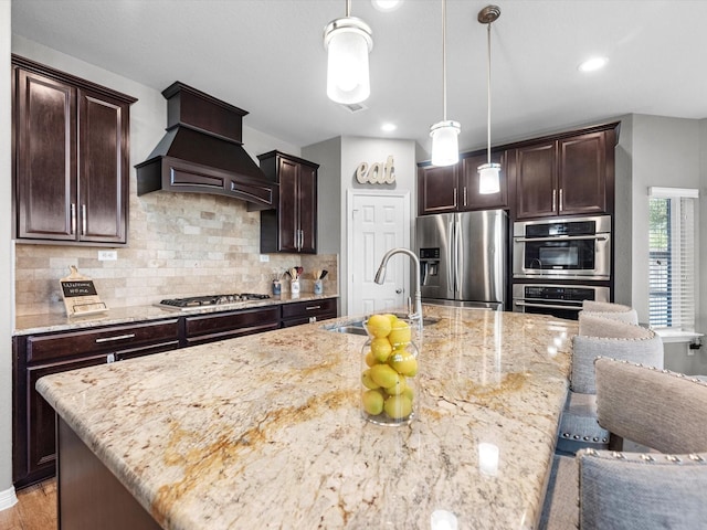 kitchen with appliances with stainless steel finishes, decorative light fixtures, custom exhaust hood, and sink