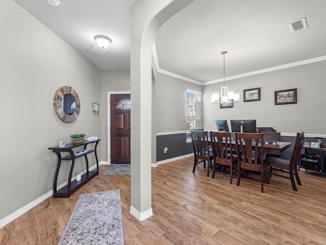 dining area featuring wood-type flooring, crown molding, and a chandelier