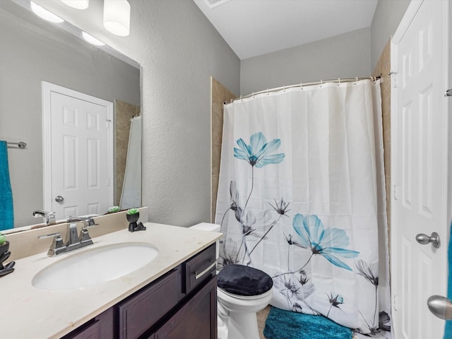 bathroom featuring walk in shower, vanity, and toilet