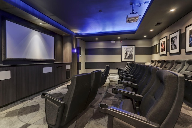 carpeted cinema featuring wood walls and a tray ceiling