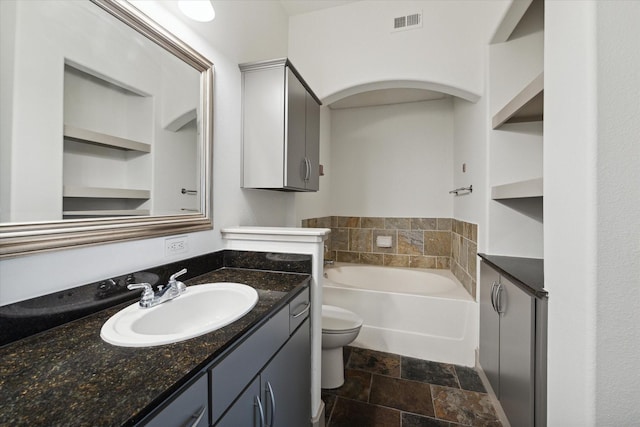 bathroom featuring vanity, toilet, and a tub