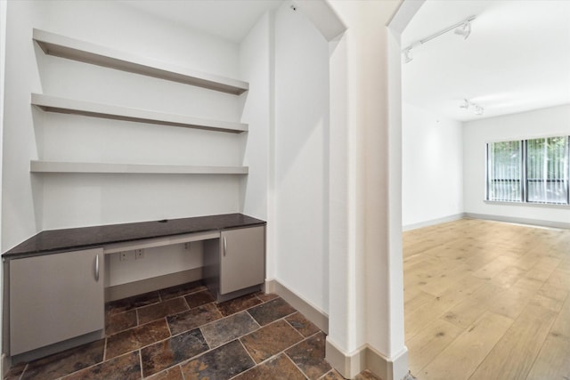 interior space featuring built in desk and rail lighting