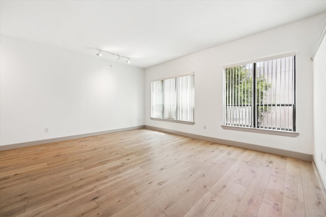 unfurnished room with plenty of natural light, rail lighting, and light hardwood / wood-style flooring