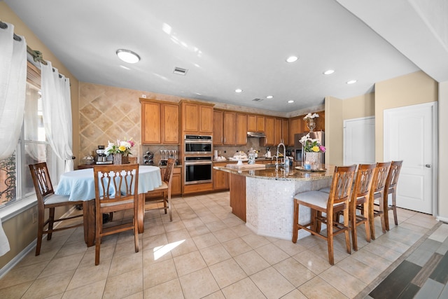 kitchen featuring sink, light tile patterned floors, tasteful backsplash, light stone counters, and stainless steel appliances