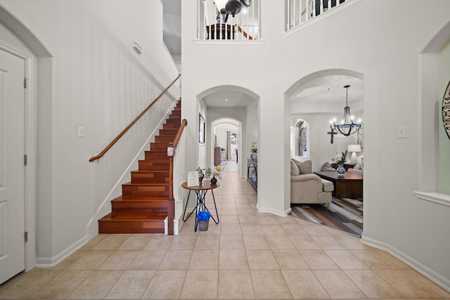 entrance foyer featuring light tile patterned floors, a towering ceiling, and a chandelier