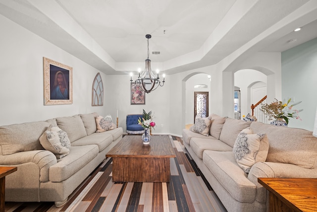 living room featuring a chandelier, hardwood / wood-style floors, and a tray ceiling