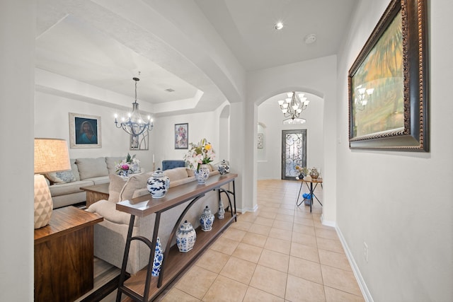 living room with light tile patterned floors, a tray ceiling, and an inviting chandelier