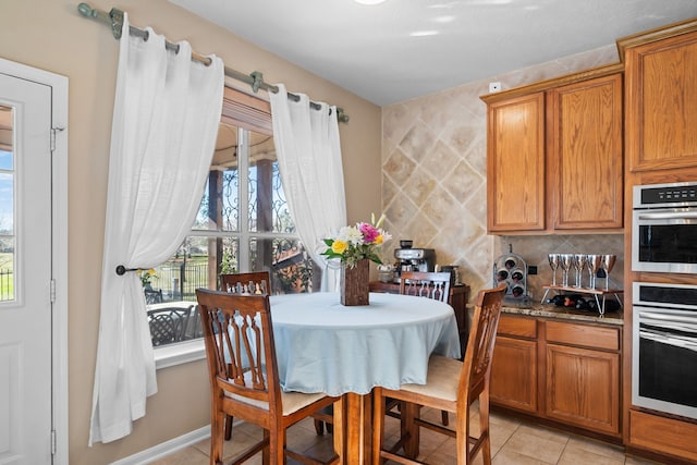 kitchen with backsplash, light tile patterned flooring, dark stone countertops, and double wall oven