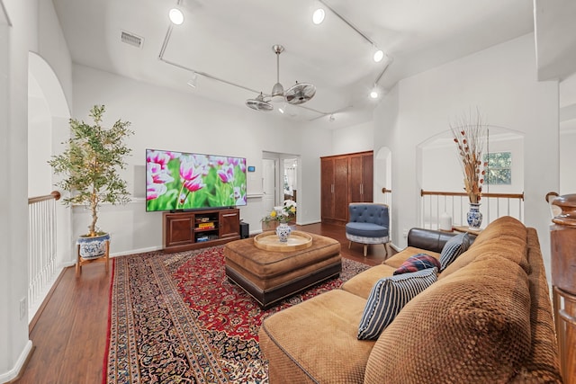 living room featuring a towering ceiling, wood-type flooring, rail lighting, and ceiling fan