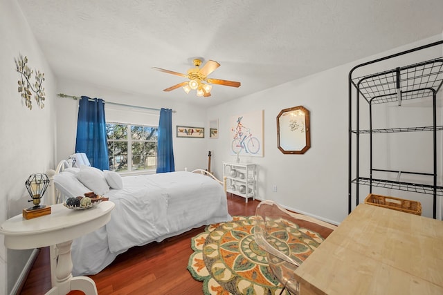 bedroom with a textured ceiling, ceiling fan, and dark wood-type flooring