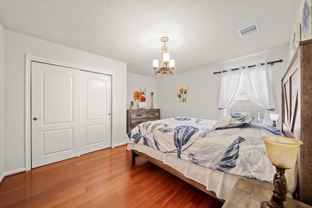 bedroom featuring a closet, hardwood / wood-style floors, and a notable chandelier